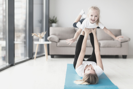 woman doing gymnastics with young girl in her living room
