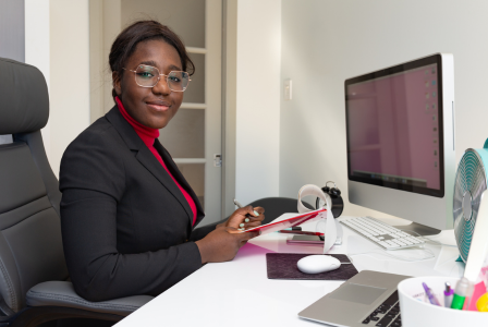 photo of a lady working at a desktop computer and smiling