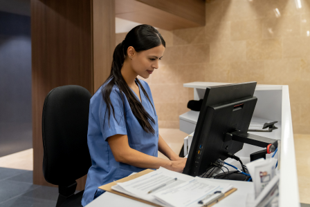 Photo of medical professional standing up and working at a computer